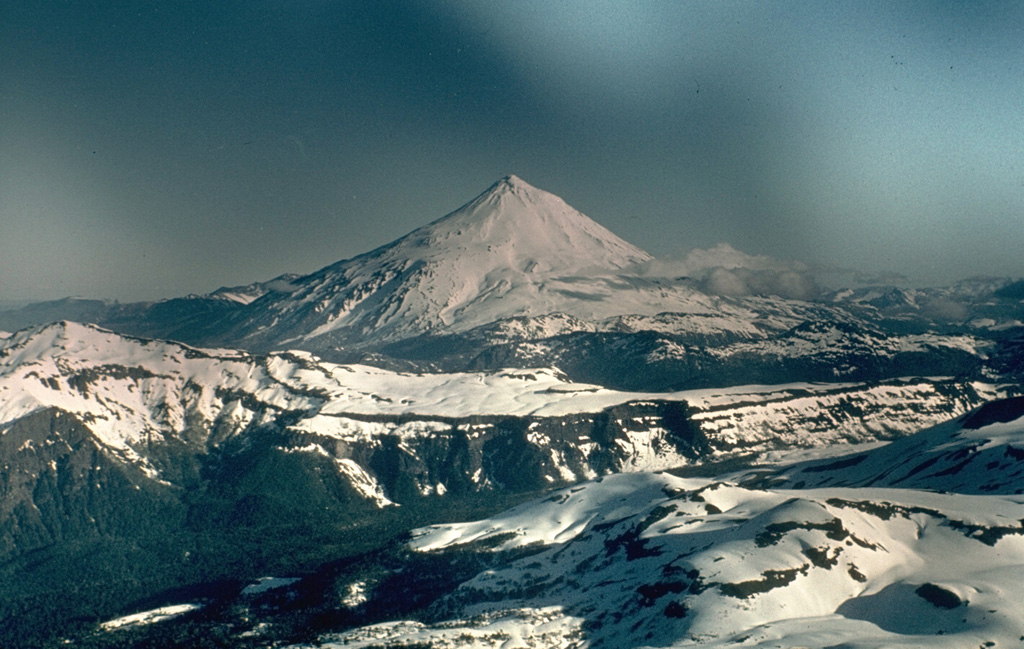 Volcán Lanín is a large conical late-Pleistocene to Holocene stratovolcano along the Chile-Argentina border.  The beautifully symmetrical, 3737-m-high Lanín, seen here from the Chilean side, rises 2500 m above its base.  A small lava dome at the summit fed blocky lava flows to the north.  A postglacial tuff ring (Volcán Arenal) is located below the SW flank of Lanín in Argentina.  A younger lava flow from Lanín covers deposits of Volcán Arenal and extends south into Lago Paimún.  No reliable reports of historical eruptions from Lanín are known. Photo by John Davidson, University of Michigan (courtesy of Hugo Moreno (University of Chile).