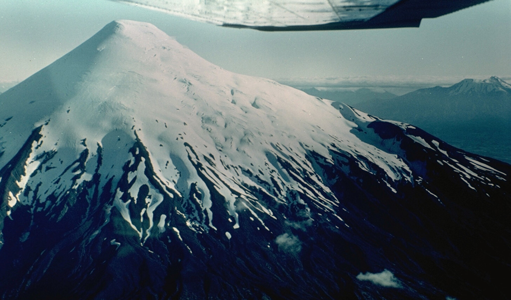 The symmetrical, glacier-clad Osorno stratovolcano forms a renowned landmark between Todos Los Santos and Llanguihue lakes.  It is seen here from the north, with Calbuco volcano visible at the extreme right.  The 2652-m-high Osorno is one of the most active volcanoes of the southern Chilean Andes.  Flank scoria cones and fissure vents, primarily on the west and SW sides, have produced lava flows that reached Lago Llanguihue.  Historical eruptions have originated from both summit and flank vents.     Photo by Hugo Moreno (University of Chile).