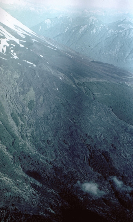 A field of fresh-looking, unvegetated lava flows blankets the SW flank of Osorno volcano.  Prominent flow levees mark channels of individual flow lobes.  Some of these lava flows were erupted from cinder cones on the SSW flank of Osorno in 1835.  Explosive activity beginning on November 29, 1834 was followed by lava effusion starting January 19, 1835 that lasted until the end of February. Photo by Hugo Moreno (University of Chile).