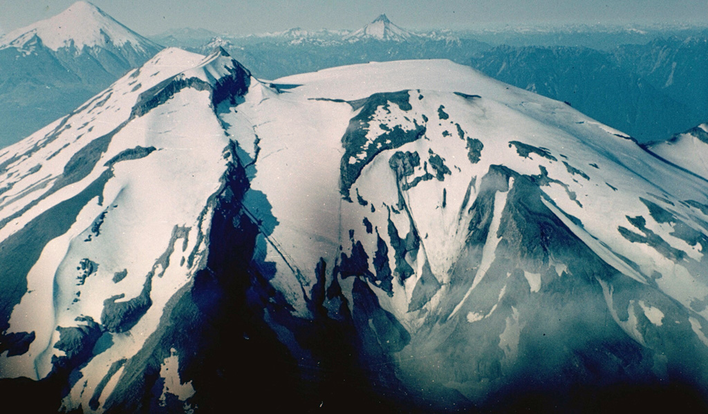 Along with its neighbor Osorno (upper left), Calbuco is one of the most active volcanoes of the southern Chilean Andes.  The summit of Calbuco, seen at the left in this view from the SW, is the remnant of an older volcano that collapsed during the late Pleistocene, producing a debris avalanche that swept NNW into Lake Llanquihue.  The smooth, snow-covered summit at the right is a young, historical lava-dome complex that postdates one of the largest historical eruptions in southern Chile during 1893-1894.     Photo by Hugo Moreno (University of Chile).