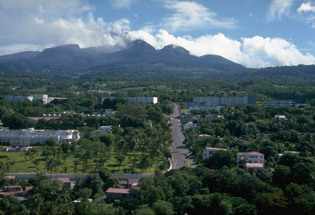 An ash plume rises above the summit of Soufrière volcano on Guadeloupe Island in October 1976 with the deserted streets of Basse-Terre, the island's capital city, in the foreground.  The 72,000 inhabitants of Basse-Terre had been evacuated since August because of concern of larger eruptions.  In November the evacuation was ended.   Photo by Richard Fiske, 1976 (Smithsonian Institution).