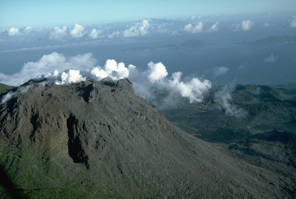 Steam pours from a fissure cutting the summit of La Soufrière in September 1976.  Intermittent phreatic eruptions had begun in July and continued until March of the following year.  This view from the north shows the Les Santes islands at the right and the tip of Dominica Island in the distance.  Photo by Richard Fiske, 1976 (Smithsonian Institution).