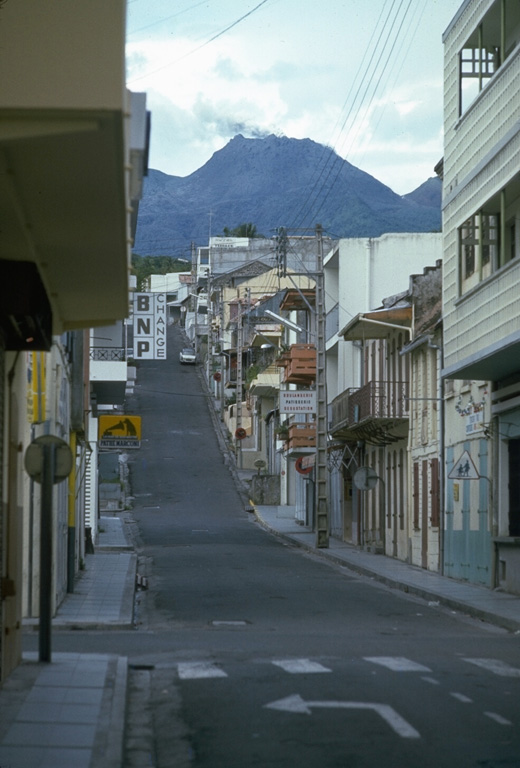 A steam-and-ash plume from the summit of La Soufrière volcano rises above the deserted streets of Basse-Terre in October 1976.  Intense controversy surrounded the evacuation of 72,000 people living on the flanks of the volcano.  The evacuation, which had resulted in major economic and social disruption, was officially ended in November.  This eruption ended without catastrophe, unlike another West Indies eruption two decades later, when the evacuated capital city of Montserrat was devastated by pyroclastic flows. Photo by Richard Fiske, 1976 (Smithsonian Institution).