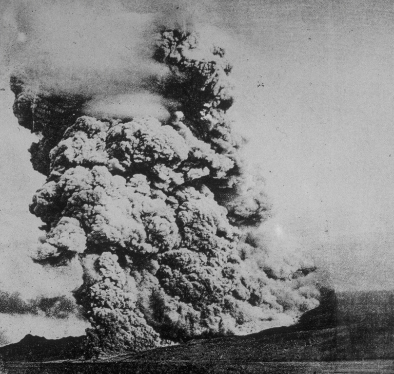 A pyroclastic flow, similiar to the one that destroyed the city of St. Pierre on Martinique on May 8, 1902, sweeps down the flanks of Mount Pelee volcano on December 16, 1902.  A towering column of ash and steam rises above the advancing pyroclastic flow, which was formed by collapse of gas-rich rocks on a growing lava dome in the summit crater.  The May 8 pyroclastic flow was substantially larger than this one, and would have covered an area wider than the entire shoreline of this photo. Photo by A. Lacroix, 1902 (from the collection of Maurice and Katia Krafft).
