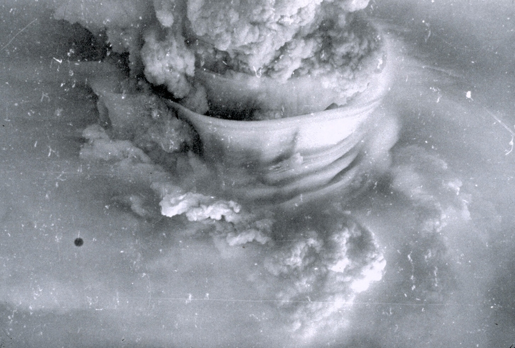 A powerful eruption column rises above Soufrière volcano on April 17, 1979.  The height of the eruption column was estimated to be 19 km.  The smooth-textured "skirt clouds" in the center of the photo were produced by condensation of subhorizontal layers of moist air that were carried up by the eruption column. Photo by Keith Rowley, 1979 (University of West Indies).