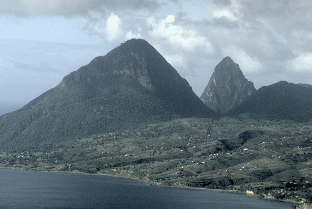 The Pitons, the dramatic landmarks of the island of St. Lucia, are the eroded plugs of two Pleistocene lava domes.  Gros Piton (left) and the even steeper Petit Piton (right) are pre-caldera lava domes west and SW of the late-Pleistocene Qualibou caldera.  The lower ridge in the right foreground is the SW-most of the 3 Bois d'Indie Franciou andesitic lava domes.  They were constructed along a NE-trending fault. Photo by Lee Siebert, 1991 (Smithsonian Institution).