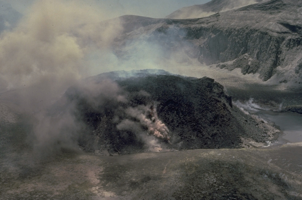 Steam rises from the margins of a growing lava dome in the summit crater of Soufrière volcano on May 7, 1979.  This photo was taken from the SW crater rim 4 days after the beginning of dome growth.  By June 18 the dome had reached a height of 110 m and was 750 m wide, covering much of the crater floor. Copyrighted photo by Katia and Maurice Krafft, 1979.