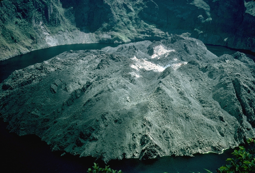 A blocky, andesitic lava dome erupted in 1971 filled much of the floor of the summit crater of Soufrière St. Vincent volcano.  This 1977 photo shows the dome, which formed a 70-m-high island in the crater lake prior to its destruction during an explosive eruption in 1979.  The 1971 eruption was unusual for Soufrière St. Vincent volcano in that it consisted of slow extrusion of lava that was not preceded by explosive eruptions. Photo by R. Howard, 1977 (Harvard University).