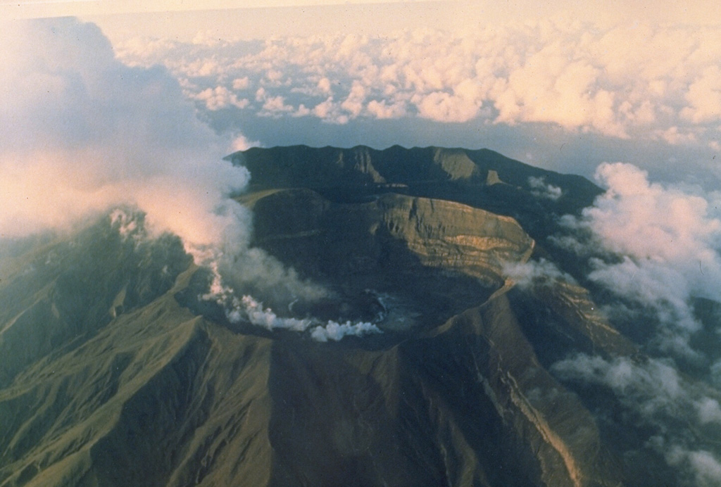 A steaming lava dome grows on the floor of the crater of Soufrière St. Vincent volcano in 1979.  Powerful explosive eruptions that emptied the crater lake and removed the 1971 lava dome took place April 13-25.  On May 3 a small lava dome appeared on the dry crater floor.  By June 18 it had reached a height of 110 m and a width of 750 m.  Diminishing dome growth took place until late October, by which time the dome was 130-m high.  This photo was taken from the SW on May 15, during the early stages of dome growth. Photo by W.H. Hunt, 1979 (Wyle Laboratories, courtesy of National Aeronautical and Space Administration).