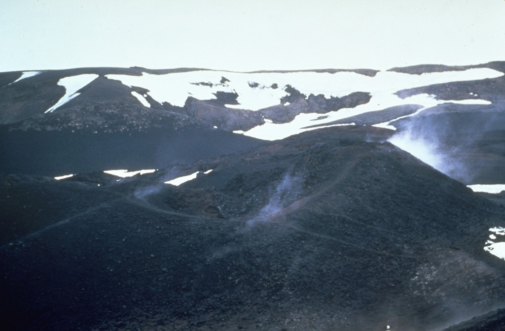 Steam rises in 1967 from a scoria cone along the Vikraborgir crater row, which was formed during an eruption of Askja volcano in 1961. The eruption began on 26 October from a fissure cutting the NE caldera floor. A chain of small scoria cones formed over the eruptive fissure, which fed lava flows that traveled 9.5 km E. Photo by Richie Williams, 1967 (U.S. Geological Survey).