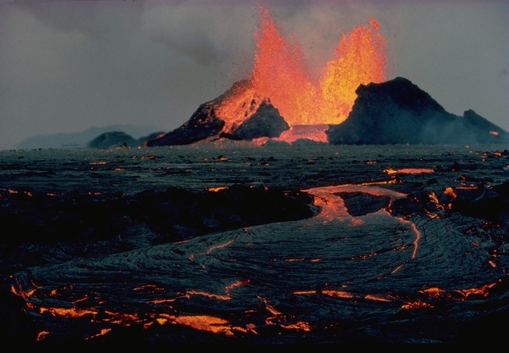 Lava fountains feed an incandescent lava flow at Krafla in September 1984.  The eruption began on September 4, following a quiet interval of 33 months, from fissures extending 8.5 km north from Leirhnjukúr.  Lava production was highest at the northern end of the fissure.  The eruption lasted until September 18, and marked the end of an intermittent eruptive episode at Krafla that began in 1975.  Copyrighted photo by Katia and Maurice Krafft, 1984.