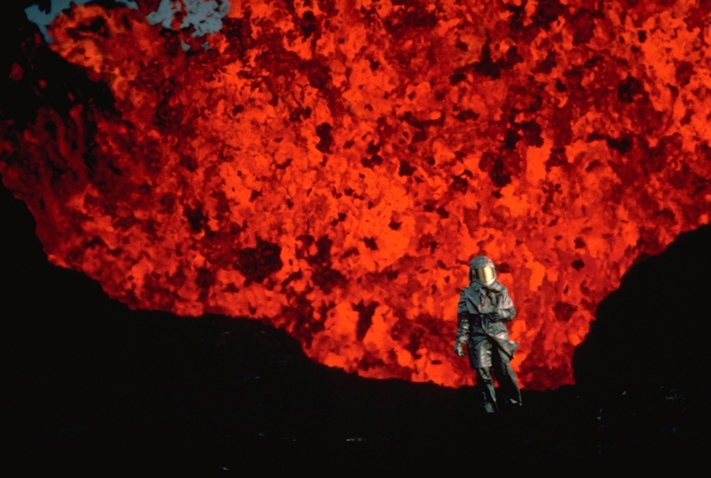 In 1984, Volcanologist Katia Krafft, wearing reflective heat-resistant gear, observes an incandescent lava fountain from Krafla volcano at close hand.  The 1984 eruption marked the end of an intermittent decade-long eruptive episode from Krafla that began in 1975.   Copyrighted photo by Katia and Maurice Krafft, 1984.