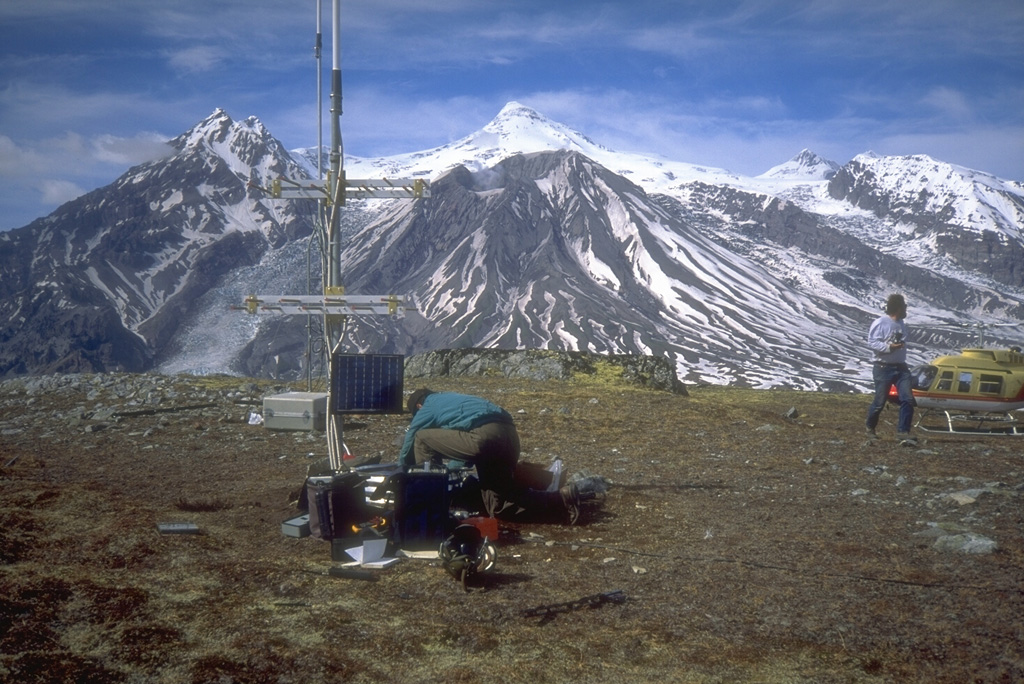Seismometers such as this one installed near Mount Spurr volcano (on skyline in background) provide the Alaska Volcano Observatory with a continuous, telemetered record of volcanic earthquakes. Scientists use this data to monitor earthquake types, locations, and magnitudes to decipher different processes under and within a volcano.  Photo by Christina Neal, 1993 (Alaska Volcano Observatory, U.S. Geological Survey).