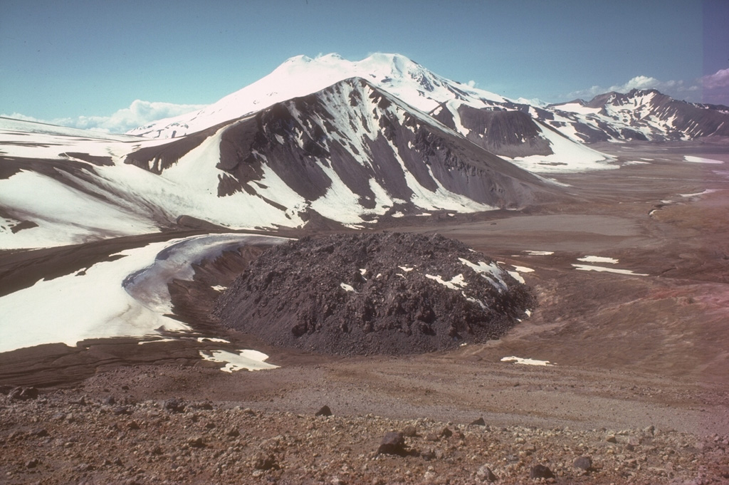 A lava dome 65 m high and 380 m wide lies within a circular ejecta ring and caps the 1912 vent of Novarupta volcano. A 60-hour-long eruption that began on 6 June 1912 was the largest eruption during the 20th century, producing The Valley of Ten Thousand Smokes pyroclastic flow deposit which forms the flat ground to the right. The face of Falling Mountain, behind Novarupta dome, was sheared off by a 2-km-wide collapse around the vent. This view from the NE shows snow-capped Mageik in the background. Photo by Tom Miller (Alaska Volcano Observatory, U.S. Geological Survey).