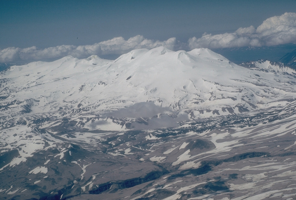 Mount Mageik is in the center of this aerial view from the east, south of Katmai Pass. Martin forms the skyline left of Mageik, and lava flows on the flanks of Trident volcano are visible to the middle right. The three volcanoes are part of a NE-SW chain across Katmai National Park. Much of the surface of Mageik is composed of Holocene lava flows. Photo by Christina Neal, 1990 (U.S. Geological Survey, Alaska Volcano Observatory).