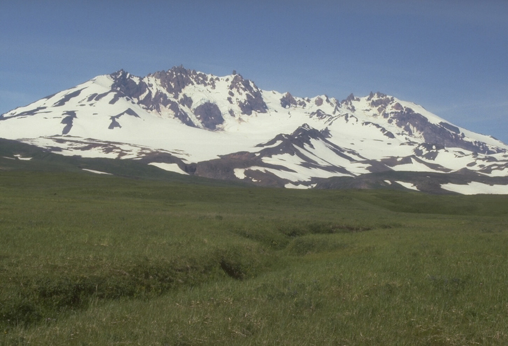 Mount Recheschnoi on Umnak Island has been extensively eroded by glaciers. This 1985 view from the SW shows the NE-SW-trending summit ridge, which is contains deep valleys. Holocene cones and lava domes are on the E and W flanks, and a large thermal area including hot springs and a geyser is on the NE flank. Photo by Chris Nye (Alaska Division of Geological & Geophysical Surveys).