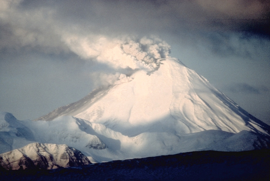 A gas-and-ash plume, seen here from the E, rises from a fissure across the summit of Kanaga on 27 January 1994. Eruptive activity began in mid-1993 and continued intermittently through most of 1995. Ash fell on the village of Adak 25 km to the E on at least one occasion. On 27-28 July incandescent lava flows were first visible on the flank and by the end of the month they reached the NW coast. Photo by E.V. Kleff, 1994 (U.S. Fish and Wildlife Service, courtesy of Alaska Volcano Observatory).