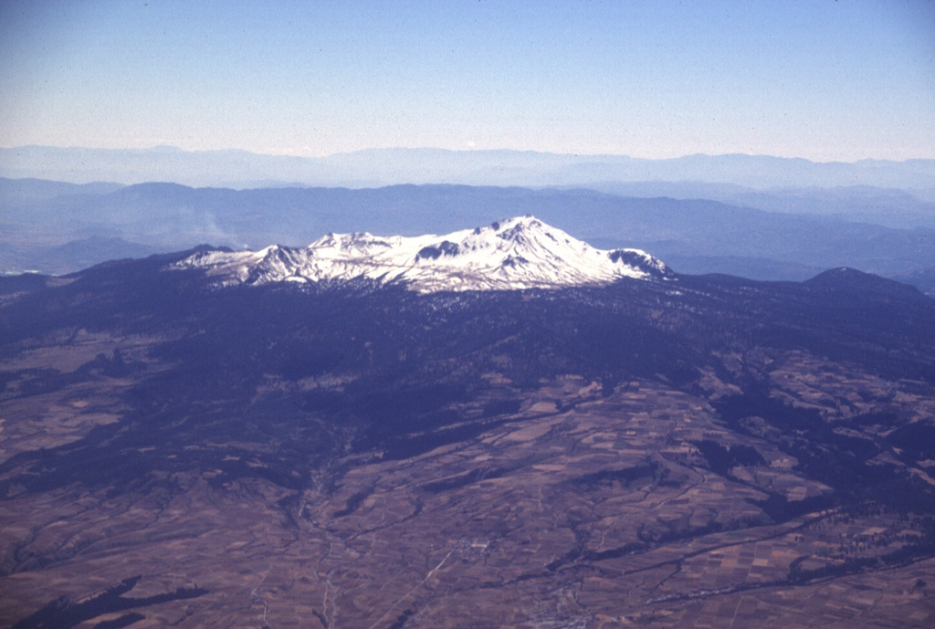 Nevado de Toluca is seen here from the NW. It is a broad, complex stratovolcano with a 1.5-km-wide summit crater that opens to the east. A lava dome in this crater separates two lakes, known as the lakes of the Sun and Moon, which can be reached by the road seen ascending diagonally across the snow-covered slopes. Photo by Lee Siebert, 1997 (Smithsonian Institution).