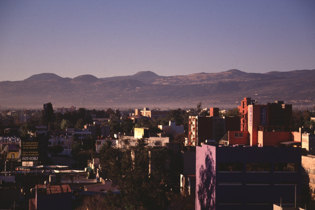 Young scoria cones of the Chichinautzin volcanic field appear on the skyline above Mexico City. Many of the more than 150 small cones within the volcanic field are of Holocene age. At least two of the cones erupted less than 2,000 years ago, producing lava flows that impacted inhabited areas. Photo by Lee Siebert, 1997 (Smithsonian Institution).