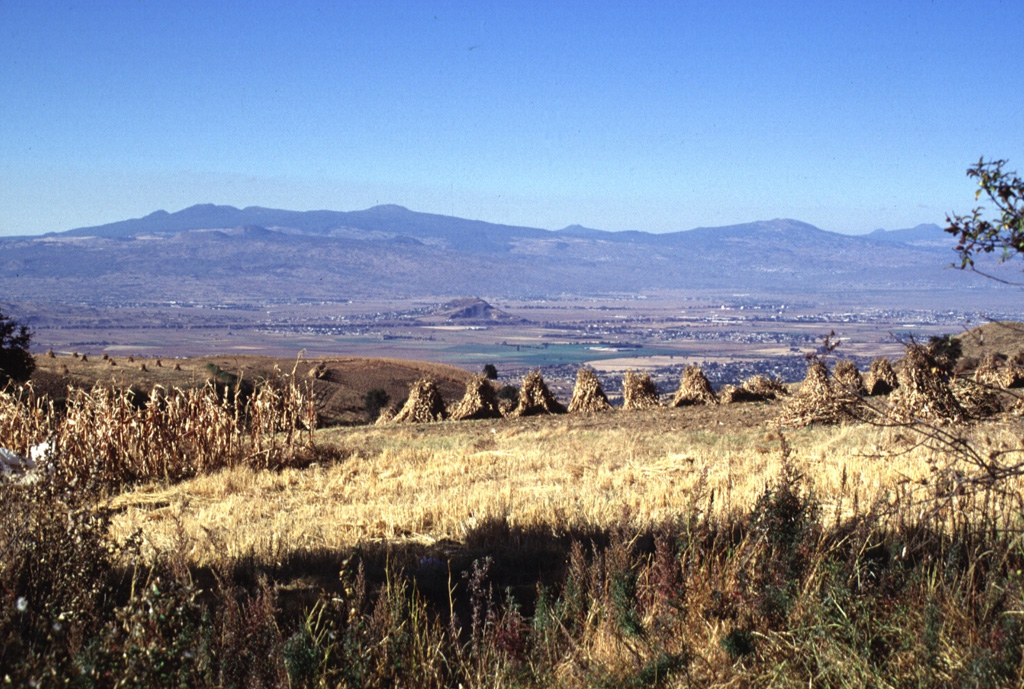 The SE part of the Chichinautzin volcanic field, seen here from the east on the flanks of the Sierra Nevada, forms a major topographic barrier at the southern end of the Valley of Mexico. Several small shield volcanoes, including Volcán Tláloc, appear on the horizon. The shield volcanoes have smaller cones on their flanks, some of which were also constructed on the floor of the Valley of Mexico. Photo by Lee Siebert, 1997 (Smithsonian Institution).