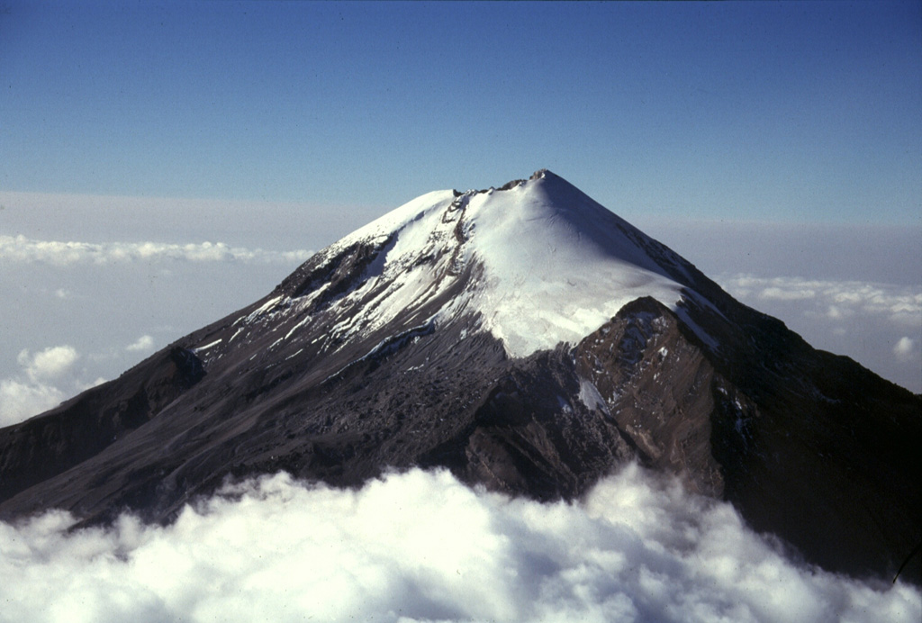 Pico de Orizaba (Volcán Citlaltépetl) rises 4,500 m above the Gulf of Mexico coastal plain. Its summit contained a 500-m-wide crater that was 300 m deep at the time of this 1997 photo. It is seen here from the NNE with the Jamapa glacier to the right above the NW-flank peak of Sarcofago (right center). The present summit cone was constructed during the Holocene, overtopping previously collapsed edifices.  Photo by Gerardo Carrasco-Núñez, 1997 (Universidad Autónoma Nacional de México).