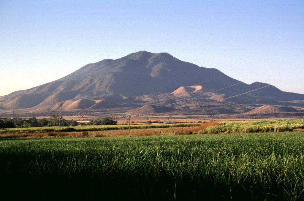 The eroded Sangangüey edifice was constructed during the Pleistocene and its flanks contain 45 scoria cones, some of which have erupted during the Holocene. The cone forming the peak on the lower right horizon and the cone highlighted by the sun below and to the right of the summit in this view from the south are among the youngest. Photo by Lee Siebert, 1997 (Smithsonian Institution).