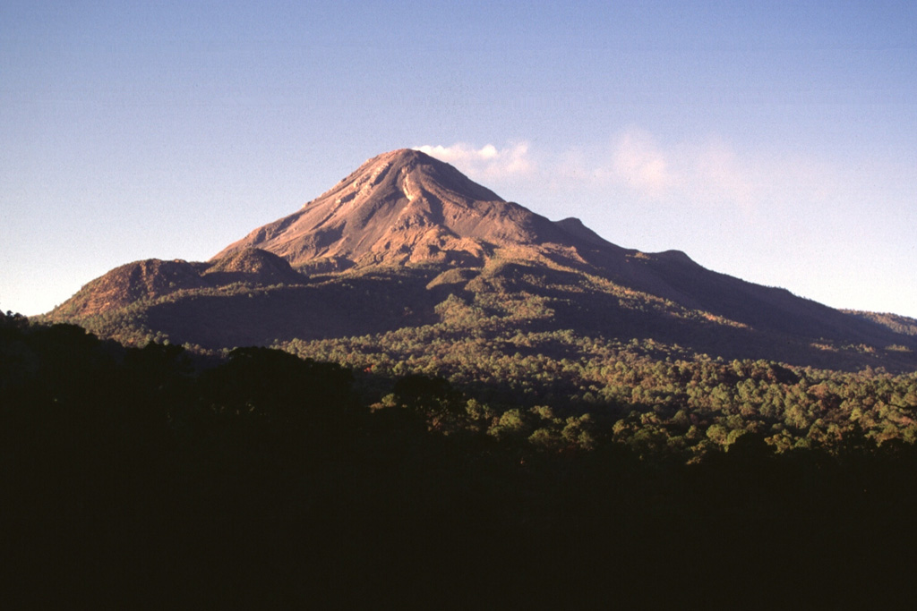 Two lava domes, known as Los Hijos del Volcán, form the two hills on the southern flank just below the left horizon of Colima. They are the southernmost of the Colima volcanic complex vents, which have erupted further towards the south through time. The 1981-1982 lava flow forms the lobe descending diagonally from the summit to the left. Photo by Lee Siebert, 1997 (Smithsonian Institution).