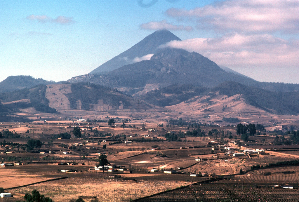 Cerro Quemado is seen here with Santa María towering directly behind it. An eruption of Cerro Quemado, part of the Almolonga lava dome complex, took place in 1818. The lava flow that forms the left-hand ridge of Cerro Quemado in this view from the NE was extruded from the east-central flank and traveled 2.5 km towards the towns of Zunil and Almolonga. Minor explosive eruptions accompanied the extrusion and produced ashfall on nearby hills. Photo by Lee Siebert, 1993 (Smithsonian Institution).