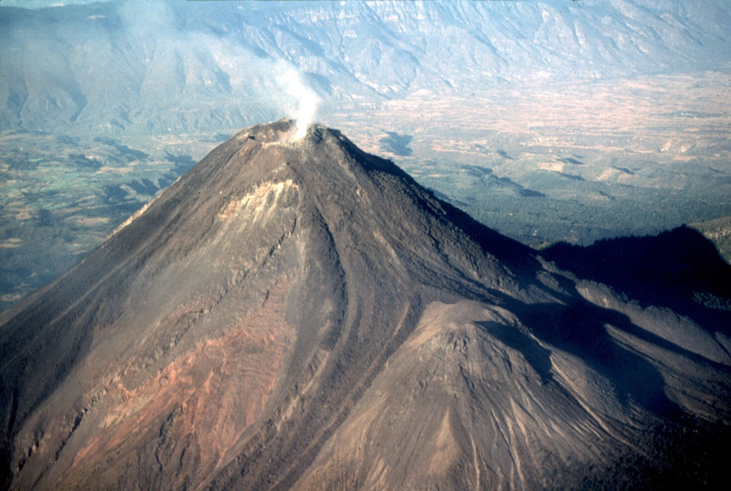 The NE-most of two lava flows produced during the 1975-76 eruption descended the flank of the summit cone until it encountered the 1869 El Volcancito lava dome (lower right). The flow then bifurcated into two lobes to the north and south. The Colima graben floor to the upper left is blanketed by debris avalanche deposits that formed during collapse of previous edifices. Photo by Warren Huff, 1997 (University of Cincinnati).