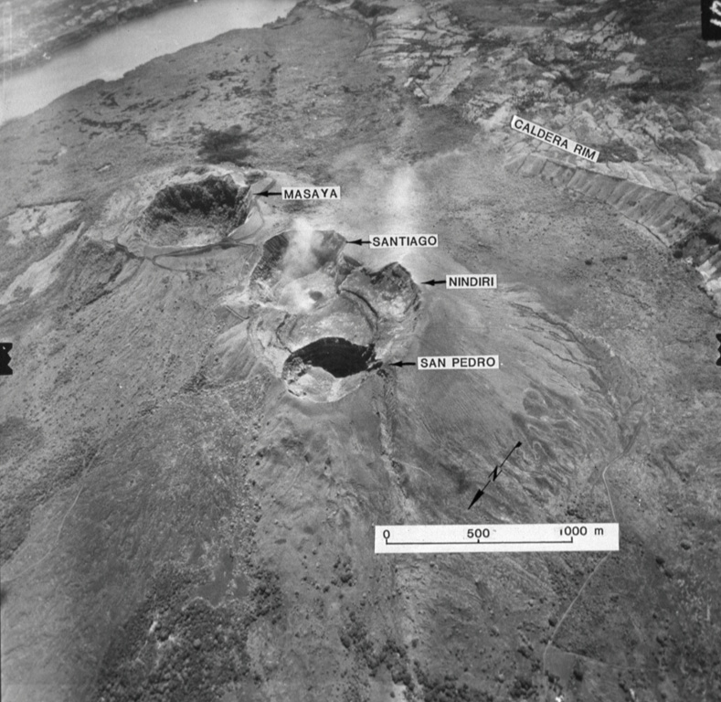 An aerial oblique photo from the NW shows the summit crater complex of Masaya volcano.  The wall of the 6 x 11 km wide caldera inside which the central cone complex was constructed can be seen at the upper right and the extreme upper left (where it contains Lake Masaya). Aerial photo by Instituto Geográfico Nacional, 1975 (courtesy of Jaime Incer).