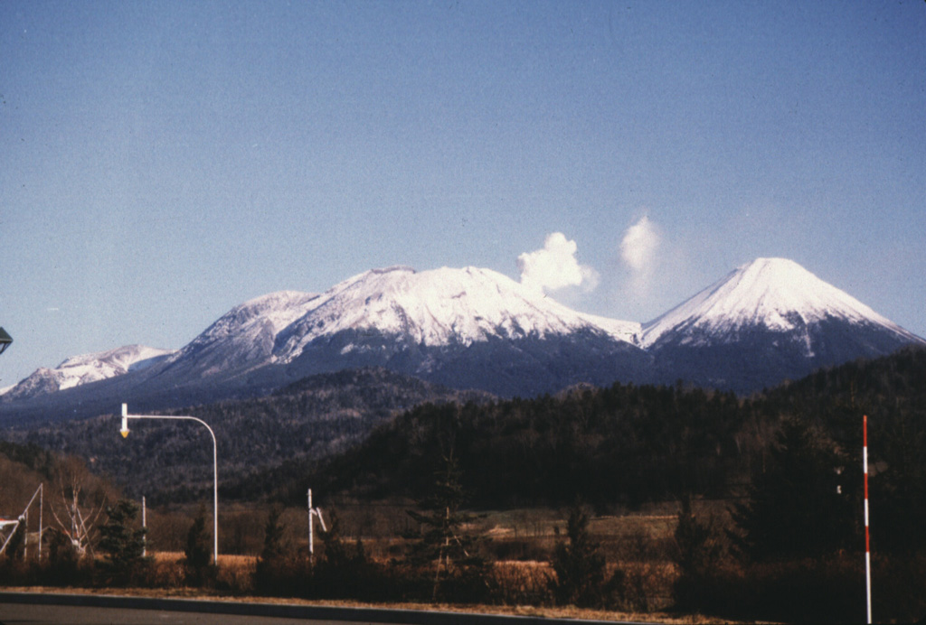 Oakandake, the largest post-caldera cone at Akan volcano, is seen here from the W across the Akan Caldera lake. It was constructed at the NE end of the 13 x 14 km caldera, opposite a cluster of stratovolcanoes at the SW end. Meakan in the SW group has been frequently active. Photo by Wataru Hirose, 1996 (Hokkaido University).