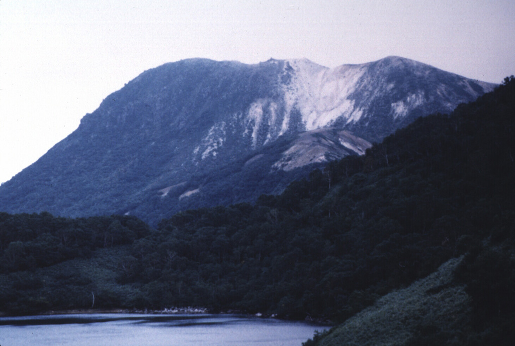 Onuma lake in the foreground is surrounded by Iwaonupuri (background), Nitonupuri, and Waisuhorun volcanoes. The latter two are located on the NW slope of Iwaonupuri. The younger lava dome (to the left) of Iwaonupuri overlies the older dome to the right. The contact is at the white altered area in the right-center. The eastern slope of Nitonupuri lava dome is seen at the right foreground. Photo by Yutaka Kodama, 1996 (Hokkaido University).