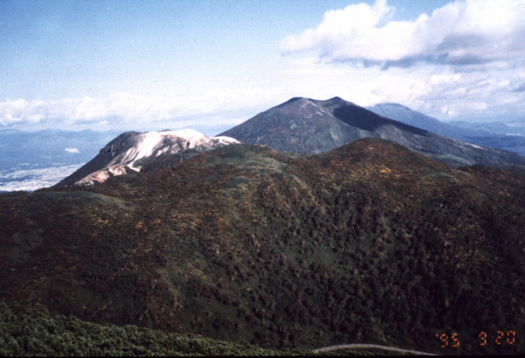 Several peaks of the Niseko volcano complex are seen in this view looking W from the  Chisenupuri summit. From front to back are the forested Nitonupuri, light-colored, flat-topped Iwaonupuri, and Niseko-Annupuri. Yotei volcano is visible in the distance to the right of Niseko-Annupuri. Photo by Yutaka Kodama, 1995 (Hokkaido University).
