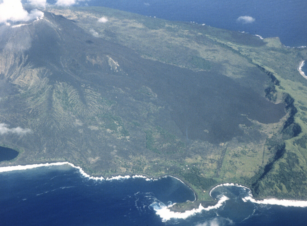 An aerial view of Pagan volcano from the W in August 1981 shows dark lava flows from the May 1981 eruption that descended the S flank as far as the arcuate caldera wall. The flows originated from a vent along a notch on the south rim of the summit crater early in an eruption that began on 15 May. This was the southernmost of three vents that were active during the 1981 eruption. Photo by U.S. Navy, 1981.