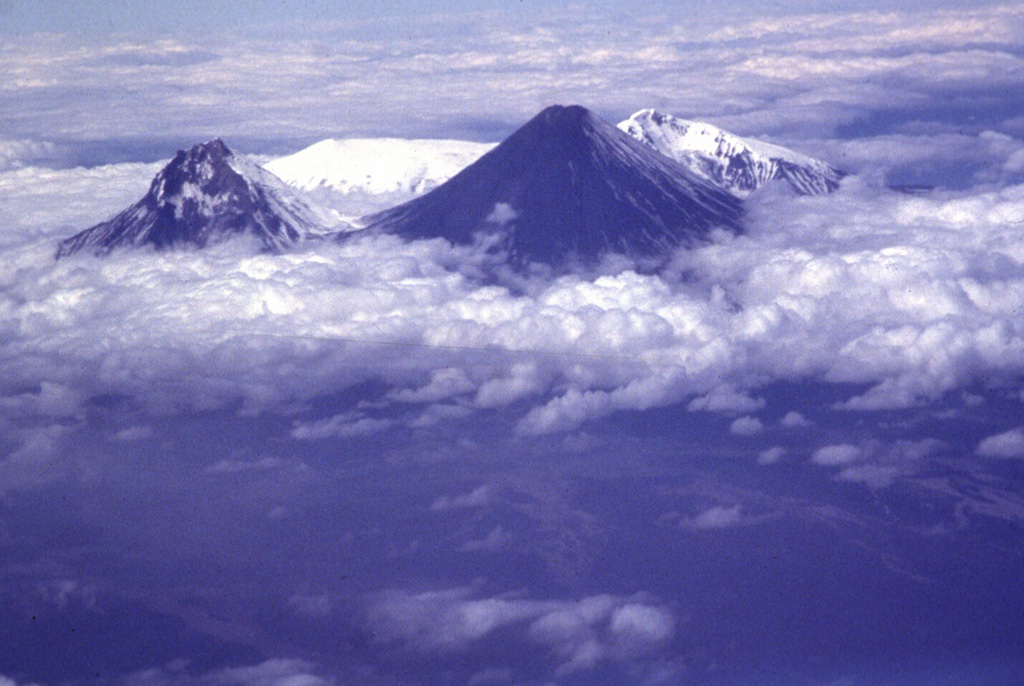 Kamen (left), Klyuchevskoy (right), and the broad snow-capped Ushkovsky behind them to the west, form the northern end of the Klyuchevskaya volcano group. Ushkovsky consists of the flat-topped Ushkovsky volcano on the left, which is capped by an ice-filled 4.5 x 5.5 km caldera, and the adjacent slightly higher Krestovsky peak on the right.  Photo by Phil Kyle, New Mexico Institute of Mining and Technology, 1996 (courtesy of Vera Ponomareva, IUGG, Petropavlovsk).