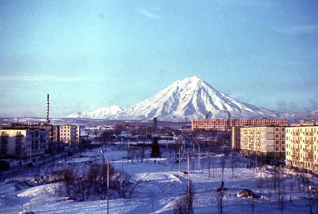 Koryaksky is seen here in winter from the Institute of Volcanology in Petropavlovsk, looking N down Piip Boulevard. The eastern flank of the volcano contains deep radial valleys exposing lava flows that form much of the volcano. Koryaksky is located along a NW-SE-trending volcanic chain beginning in the NW with the Pleistocene volcanoes of Aak and Arik that are visible to the left. Photo by Vera Ponomareva, 1997 (Institute of Volcanic Geology and Geochemistry, Petropavlovsk).