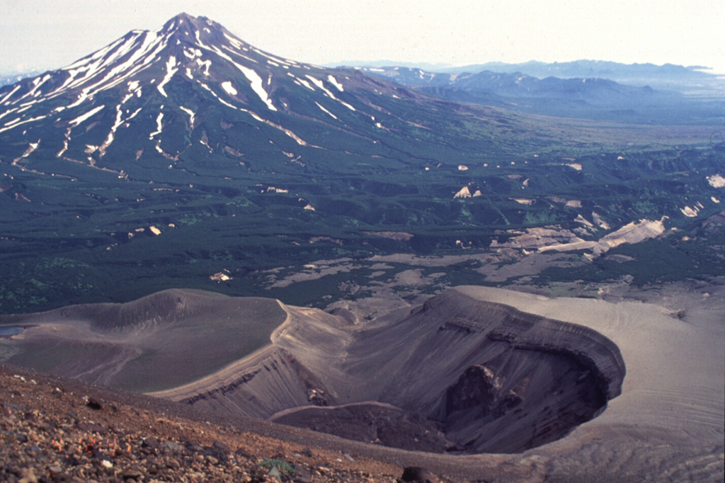 The maar crater in the foreground formed during an eruption in 1901 on the NE flank of Iliinsky volcano. Light-colored tephra was deposited around the rim of the crater and cover the flanks of the volcano. At the end of the eruption lava was extruded on the floor of the 200-m-deep, 1-km-wide crater. Zheltovsky is the volcano to the left of this image. Photo by Philip Kyle, New Mexico Institute of Mining and Technology, 1996 (courtesy of Vera Ponomareva, IVGG, Petropavlovsk).