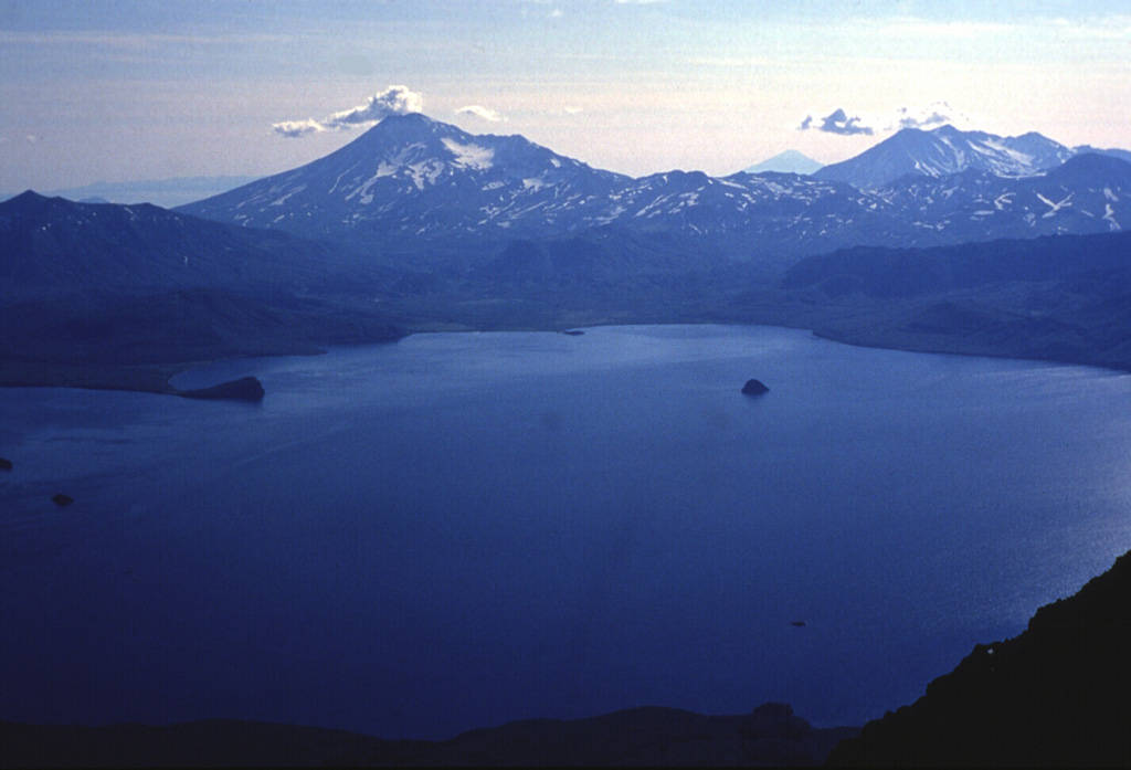 Kambalny (left) and Koshelev (right) rise above the SW shore of Kurile Lake caldera at the southern tip of Kamchatka. The caldera formed in two stages, the first about 41,500 radiocarbon years ago and the second about 7,600 years ago during one of Kamchatka's largest Holocene eruptions. The small island (right-center) is the lava dome referred to as the "Heart of Alaid”. The peak on the distant horizon at right-center is Alaid in the Kuril Islands. Photo by Nikolai Smelov, 1996 (courtesy of Vera Ponomareva, Inst. Volcanic Geology & Geochemistry, Petropavlovsk).