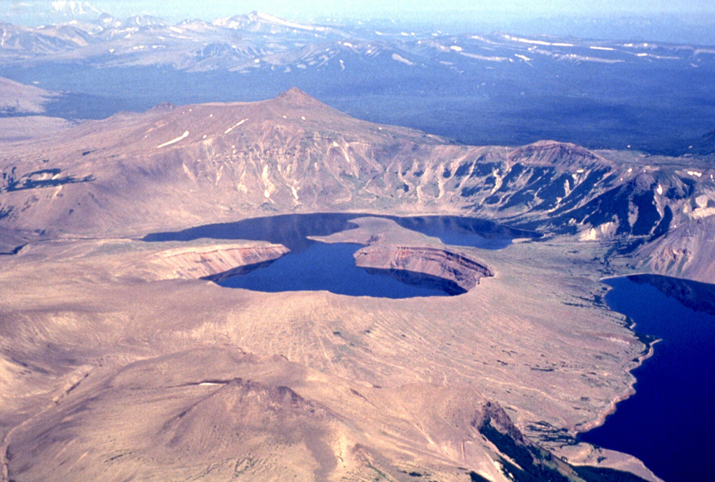 Ksudach, the large volcano seen here from the SW, contains five calderas with the northern of two caldera lakes (center) forming an embayment in Shtyubel' Crater. Situated within the youngest caldera, Ksudach V, Shtyubel’ has been active since about 1,600 years ago and an eruption in 1907 was one of Kamchatka's largest in historical time. Photo by Nikolai Smelov, 1996 (courtesy of Vera Ponomareva, Institute of Volcanic Geology and Geochemistry, Petropavlovsk).