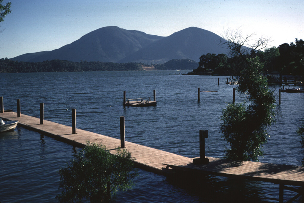 Mount Konocti, a twin-peaked complex dacitic volcano of Pleistocene age on the south-central shore of Clear Lake, is the most prominent feature of the Clear Lake volcanic field.  Wright Peak (left) is a rhyodacitic and dacitic lava dome with associated lava flows, and Buckingham Peak (right) is composed of dacitic lava flows capped by an eroded basaltic-andesite cinder cone.  The flat ridge extending across the photo in front of Mount Konocti is a peninsula of Cretaceous-Jurrasic rocks of the Franciscan formation. Photo by Lee Siebert, 1967 (Smithsonian Institution).