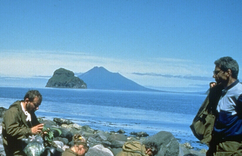 Fuss Peak in the distance forms a peninsula on the SW coast of Paramushir Island. The cone has a 700-m-wide, 300-m-deep crater. Well-preserved lava flows were emplaced on the middle and lower flanks, particularly on the E and SE sides. A volcanological field party in the foreground are on the shore of Shirinki Island. Photo by Oleg Volynets (Institute of Volcanology, Petropavlovsk).