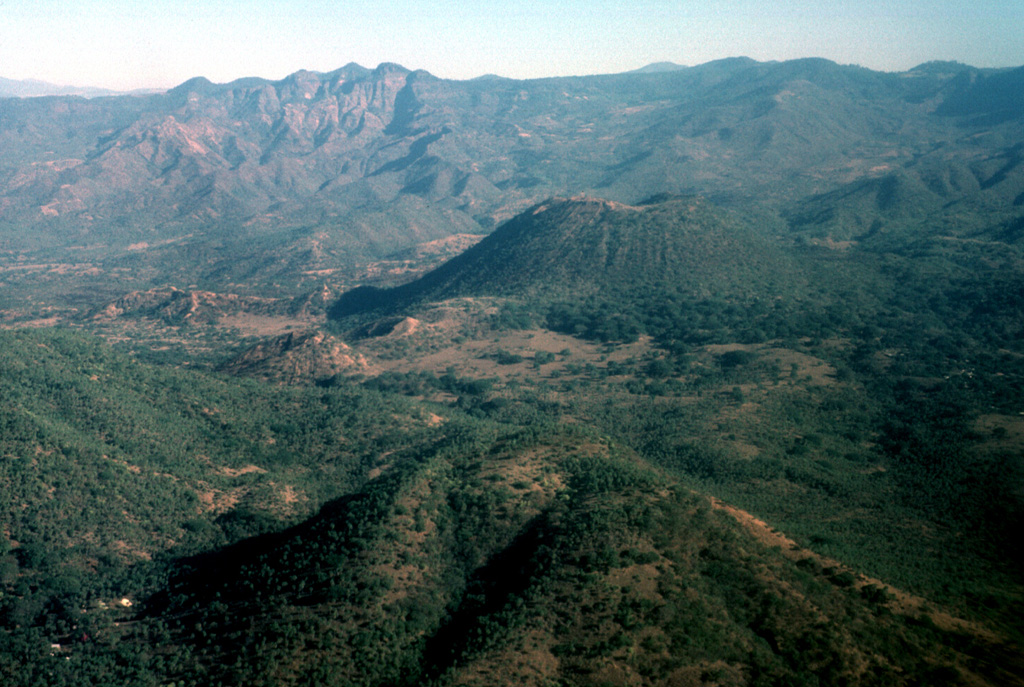 The Jorullo cone (right-center) is seen here from the SSW with Cerro la Pilita cone in the foreground. The small, less-vegetated cones immediately to the left are the SW-flank vents that produced lava flows during the middle part of the 1759-1774 eruption. Cerro la Pilita is an older cone that produced pre-historical lava flows along a narrow channel to the SW. Photo by Jim Luhr, 1997 (Smithsonian Institution).