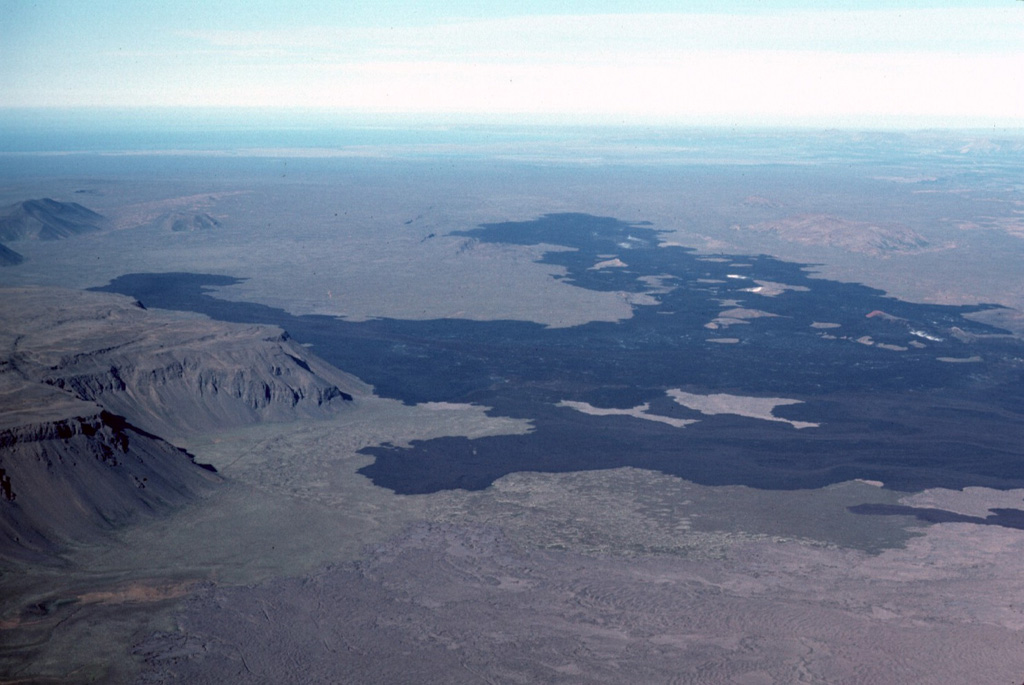 The dark lava flow field of the 1975-1984 rifting episode of Krafla extends about 16 km N into the distance, and reached the base of the eastern Gæsafjöll cliffs (left). One of Iceland’s table mountains, Gæsafjöll formed as a result of repeated eruptions through a glacial icecap. Photo by Michael Ryan, 1984 (U.S. Geological Survey).