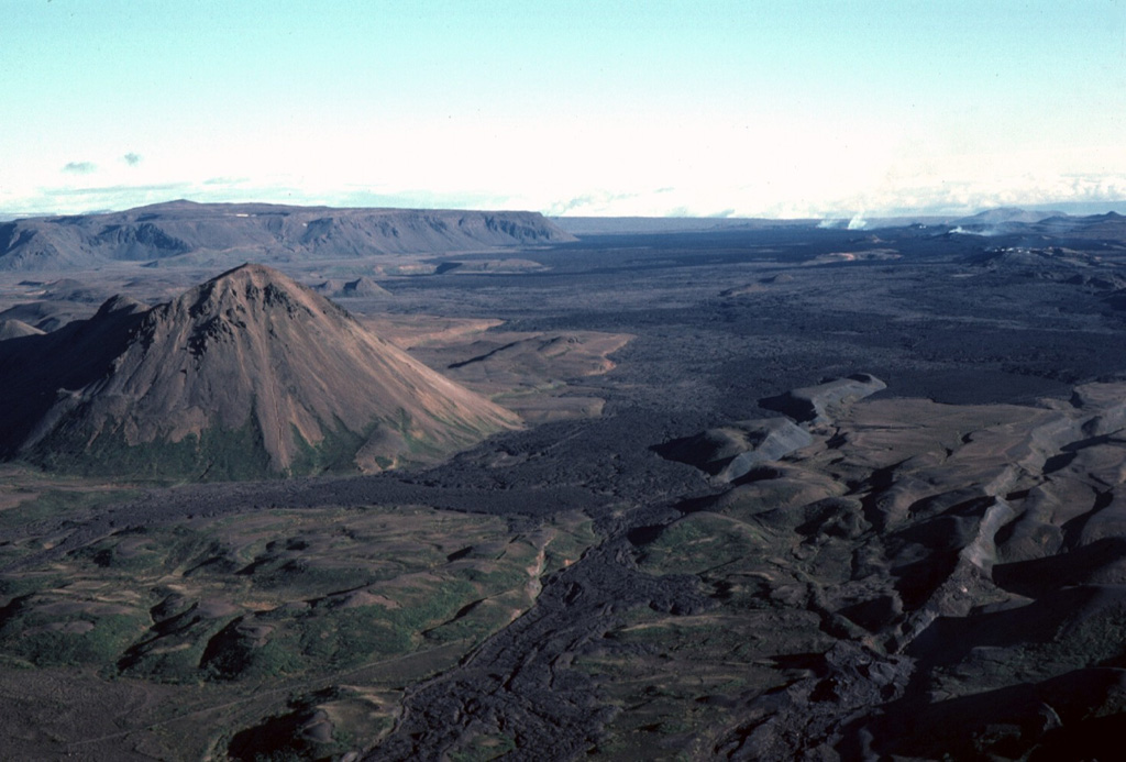 The Krafla central volcano, located NE of Mývatn lake, is a topographically indistinct 9-km-wide caldera that is cut by a N-S-trending fissure system. This view from the south looks toward the center of the caldera with the rhyolitic lava dome of Hlidarfjall on the left and prominent fissures cutting across the caldera at the right.  Photo by Michael Ryan, 1984 (U.S. Geological Survey).