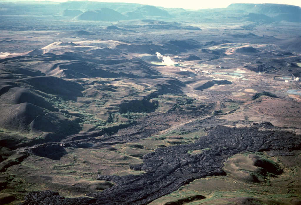 The dark lava flows in the foreground were emplaced during a series of eruptions known as the "Myvatn Fires" between 1724 and 1729. Lava flows covered much of the western floor of Krafla caldera and extended beyond the caldera to the north, and south into Myvatn lake. It is these southern flows seen here, with small lakes and a steam plume in the Namafjall and Myvatn geothermal areas at their distal end (center). The Hverfjall cone is just out of view to the top right. Photo by Michael Ryan, 1984 (U.S. Geological Survey).
