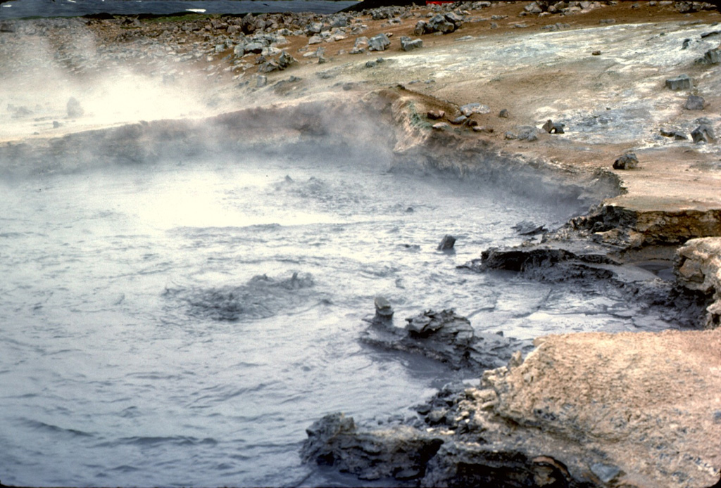 The Námafjall and Myvatn geothermal areas contains boiling mudpots such as these, numerous fumaroles, hot pools, and extensive areas of hydrothermally altered ground (the lighter-colored ground surface). Thermal activity keeps the ground warm enough in nearby areas so that there is no risk of frost at night. Farmers have taken advantage of this natural heat source to grow potatoes in an area of northern Iceland where that would normally not be possible. Photo by Michael Ryan, 1984 (U.S. Geological Survey).