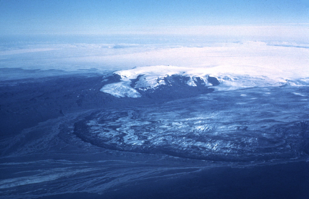 Kverkfjöll, seen here from the north, is a subglacial volcano at the northern end of the Vatnajökull icecap, west of Bárdarbunga. The Dyngjujökull glacier, an outflow sheet of the Vatnajökull icecap, appears in the foreground during a 1977 glacial surge. The dark ridge on the left, seen here separated from the outflow sheet by a stream, is a lava flow from about 4,500 to 6,100 years ago.  Photo by Oddur Sigurdsson, 1977 (Icelandic National Energy Authority).