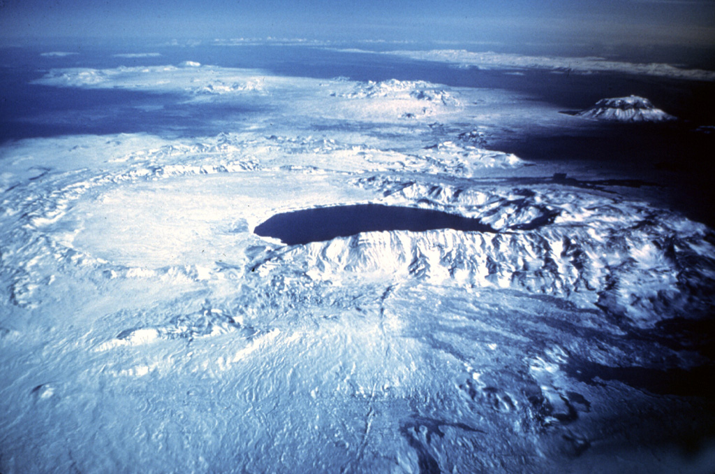 Askja, seen here in an aerial view from the south, is a large central volcano truncated by three overlapping calderas. The youngest caldera, formed during the large 1875 eruption, is filled by Öskjuvatn lake (center). This caldera partially truncates the largest Askja caldera, whose floor forms the flat-surfaced area left of the lake now filled with recent lava. The prominent snow-capped peak on the right is Herðubreið, which has not been active in the Holocene. Photo by Oddur Sigurdsson, 1977 (Icelandic National Energy Authority).