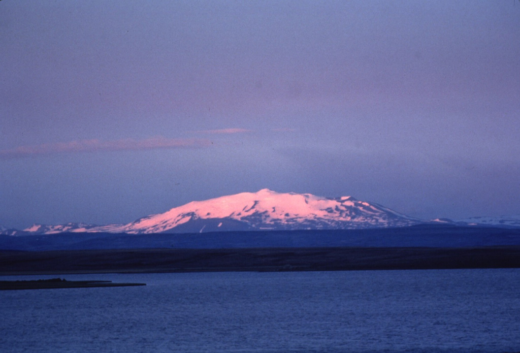 Twilight colors shade the snow-capped slopes of Hekla, one of Iceland's most active volcanoes. Hekla's elongated profile is apparent in this view from the north of the 5.5-km-long summit ridge. The Heklugjá fissure which runs along the length of the ridge has been the site of numerous historical eruptions and is often active along its full length. Photo by Bill Rose, 1980 (Michigan Technological University).