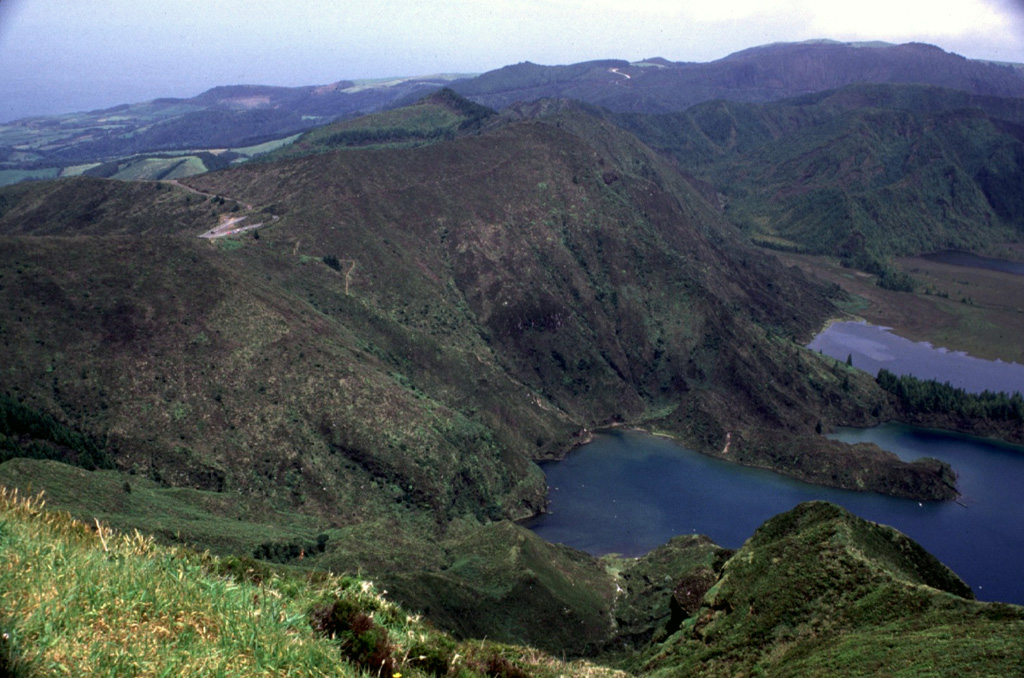 The forested ridge in the center of the photo is part of the northern rim of the approximately 3.2 km diameter inner Agua de Pau caldera, which formed at the beginning of the Holocene, in an eruption dated to between 12,000 and 8,000 years ago. The Serra de Agua de Pau hills in the background mark the northern rim of an outer late Pleistocene caldera. The Lagoa de Fogo caldera lake (lower right) partially fills the inner caldera. Photo by Rick Wunderman, 1997 (Smithsonian Institution).